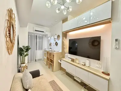 a living room with a large flat screen tv at Cozy and Stylish Unit in Fame Residences in Manila