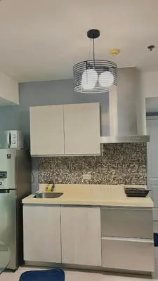 a kitchen with white cabinets and a sink at Yana's Place - Azure Residences in Manila