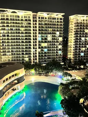 a large swimming pool in front of buildings at night at Yana's Place - Azure Residences in Manila