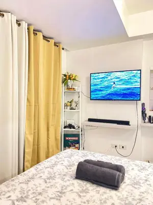 a bedroom with a bed and a flat screen tv at Yana's Place - Azure Residences in Manila