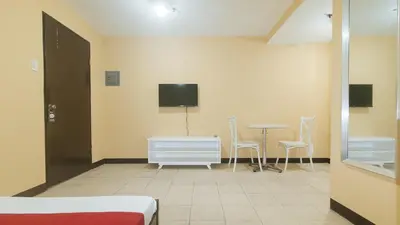 a room with a tv and a table and chairs at RedDoorz at MUBG Apartelle near Baclaran Church in Manila