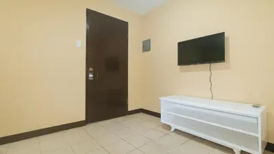 a room with a tv on the wall and a door at RedDoorz at MUBG Apartelle near Baclaran Church in Manila