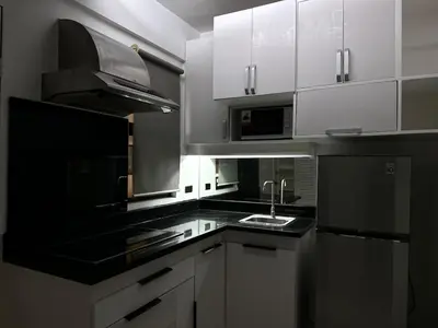 a kitchen with white cabinets and a black counter top at Modern Japanese Resort-Type Condo in Manila