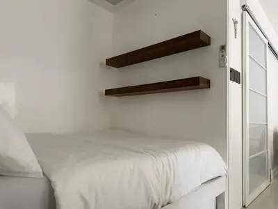 a white bedroom with a bed and a mirror at Modern Japanese Resort-Type Condo in Manila