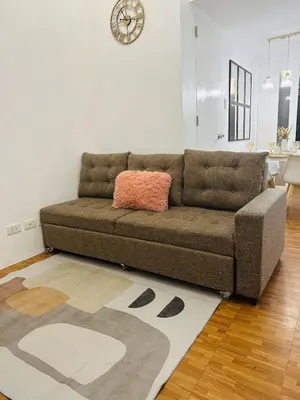 a brown couch in a living room with a rug at EDSA Cozy 3BR near MRT w Netflix and Karaoke Fun in Manila