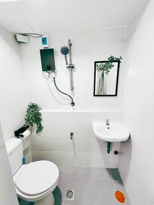 a white bathroom with a toilet and a sink at Cozy 2 BR 2 Bath Condo with Netflix and Karaoke near MRT EDSA in Manila