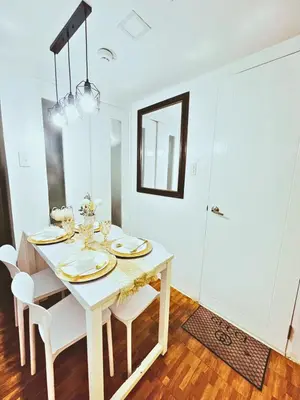 a white dining room with a white table and chairs at Cozy 2 BR 2 Bath Condo with Netflix and Karaoke near MRT EDSA in Manila
