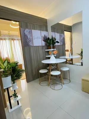 a dining room with two tables and stools and plants at Field Residences Hotel Apartments Near Manila Airport in Manila