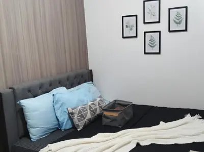 a bedroom with a bed with pillows and pictures on the wall at Mall of Asia - Pasay Condo in Manila