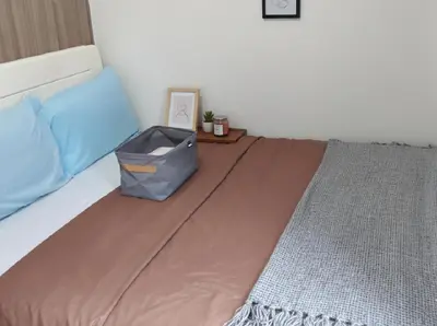 a bedroom with a bed with a blanket and a table at Mall of Asia - Pasay Condo in Manila
