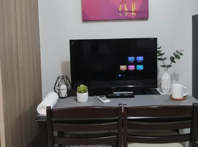 a room with a table with a large screen television at Mall of Asia Accommodation in Manila
