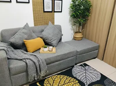 a living room with a grey couch with a table at MOA - Aseana Pasay Condo in Manila