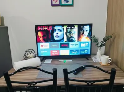 a television sitting on a wooden table with two chairs at MOA Apartment in Pasay in Manila