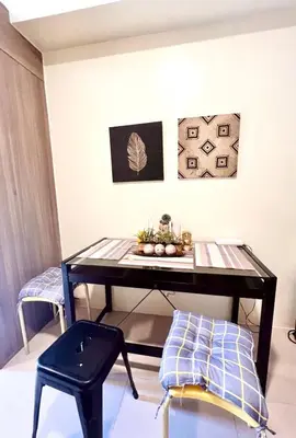 a table in a room with a stool and paintings at Central Ortigas Condo in Manila