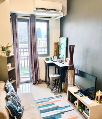 a living room with a table and a desk with a television at Ortigas Greenfield Cozy Lodge in Manila