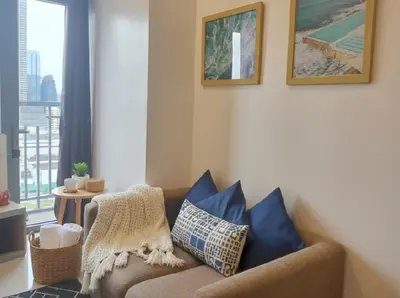 a living room with a brown couch with blue pillows at Heart of Ortigas in Manila