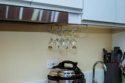 four wine glasses hanging from a rack in a kitchen at 2 BR Air condo Makati Penthouse SwimGym 300Netflix 5249 in Manila