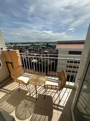 a balcony with two chairs and a table on a building at Staycation at Field Residences Near Airport in Manila