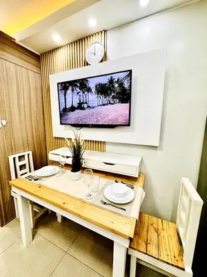 a dining room with a table and a tv on the wall at Lotus' Suite in Manila