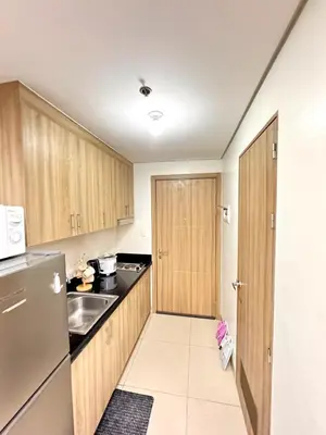 a small kitchen with wooden cabinets and a refrigerator at Lotus' Suite in Manila