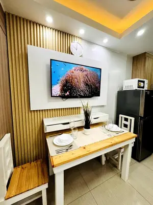 a dining room table with a television on a wall at Lotus' Suite in Manila