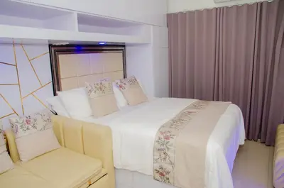 a bedroom with a large bed and two chairs at Stylish Condo at Shore 2 Residences near MOA & Airport in Manila