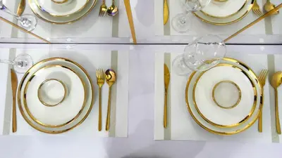 a table with gold and white plates and forks and knives at Stylish Condo at Shore 2 Residences near MOA & Airport in Manila