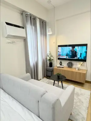 a living room with a white couch and a flat screen tv at The Niall's Suites at HOPE Residences besides SM TRECE in Trece Martires