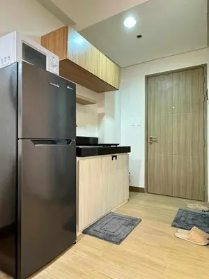 a kitchen with a stainless steel refrigerator and wooden cabinets at The Niall's Suites at HOPE Residences besides SM TRECE in Trece Martires
