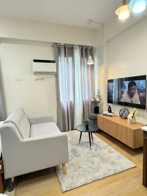 a living room with a white couch and a flat screen tv at The Niall's Suites at HOPE Residences besides SM TRECE in Trece Martires