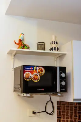 a microwave on a wall with shelves above it at Witty Weekend retreat Quirk Cozy in Manila