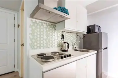 a white kitchen with a stove and a refrigerator at Azure Urban Resort Residences,BORACAY tower model unit in Manila