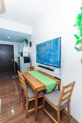 a wooden table with chairs and a television on a wall at Urban Charm Cozy Meet 51 Air Swim Gym Park 300Mb in Manila