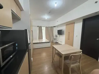 a living room with a table and a kitchen at City Front Studio in Manila