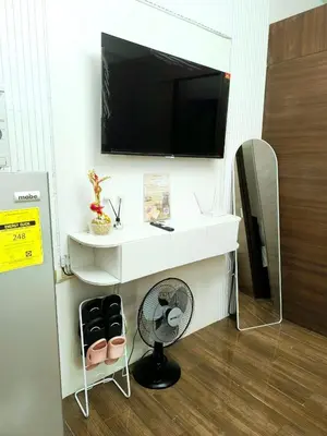 a white desk with a fan and a tv on a wall at Charming Comfort 1BR at Air Residences Makati with wifi & netflix in Manila