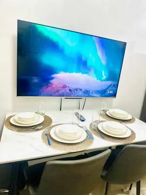 a table with chairs and plates and a tv on the wall at Cozy Retreat at Shore2 Residences in Manila