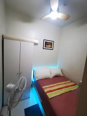 a small bedroom with a bed and a fan at Aldo shore 3 tower 2 mall of Asia in Manila