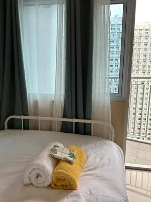 a bedroom with a bed with a towel and a window at Modern & Cozy Two BR in Jazz Residences Makati City in Manila