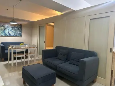 a living room with a blue couch and a table at Modern & Cozy Two BR in Jazz Residences Makati City in Manila