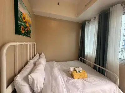 a bedroom with a bed with white sheets and a window at Modern & Cozy Two BR in Jazz Residences Makati City in Manila