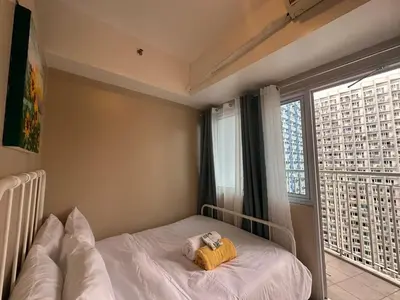 a bedroom with a bed and a large window at Modern & Cozy Two BR in Jazz Residences Makati City in Manila