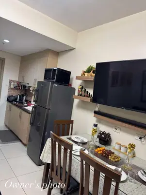 a kitchen with a table and a refrigerator and a television at JUVREY 1 BR Studio Unit with balcony in Manila