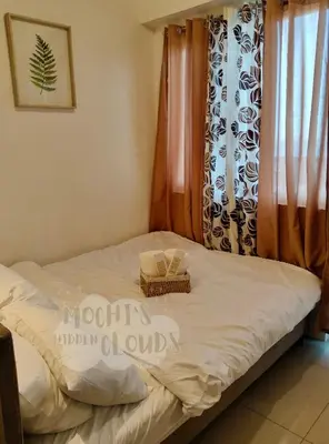 a bed with a basket on it in front of a window at Condotel with Balcony Near Airport and MOA with Games & Karaoke in Manila