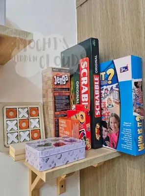 a shelf with a bunch of books and a box at Condotel with Balcony Near Airport and MOA with Games & Karaoke in Manila