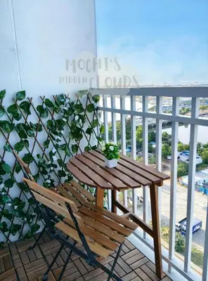 a wooden table and chairs on a balcony with a plant at Condotel with Balcony Near Airport and MOA with Games & Karaoke in Manila
