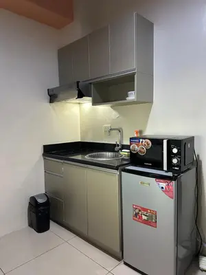 a small kitchen with a microwave and a refrigerator at Quaint Roces Studio in Manila