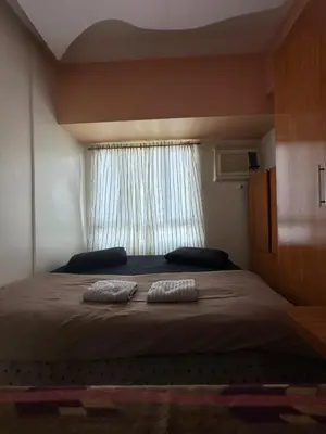 a bedroom with a large bed with two pillows on it at Quaint Roces Studio in Manila