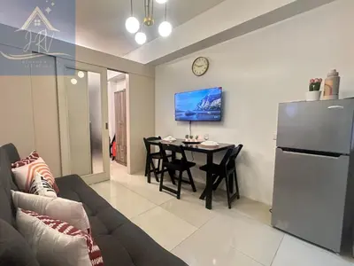 a living room with a couch and a table and a refrigerator at 1bedroom with balcony at Sea Residences near MOA and SMX in Manila