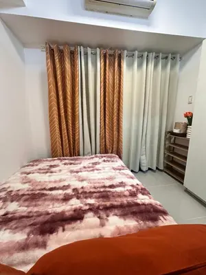 a bedroom with a bed and some curtains at 1bedroom with balcony at Sea Residences near MOA and SMX in Manila