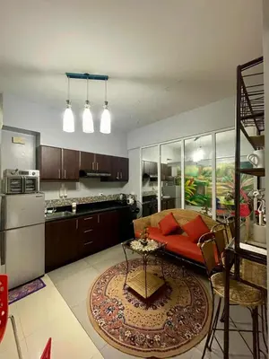 a living room with a red couch and a kitchen at Tropical unit in Manila
